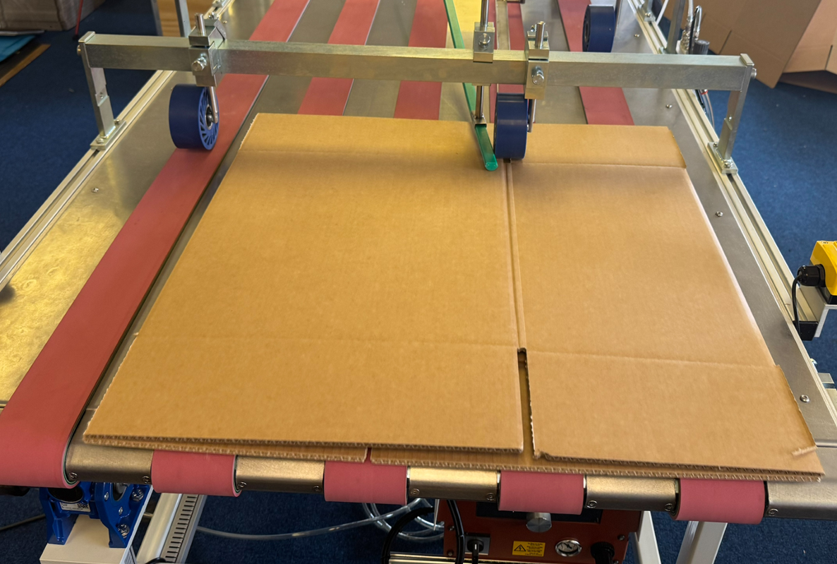 Complete and sealed box is discharged at the end of the conveyor
